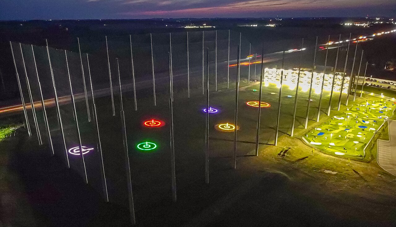 Driving range lit up at night with glowing target rings